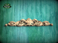 Load image into Gallery viewer, A decorative wooden carving with intricate floral and scrollwork designs is displayed against a green wooden background.
