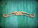 A decorative wooden carving of a floral design is displayed against a green textured background.
