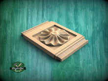 Load image into Gallery viewer, A wooden panel with a carved flower design is displayed against a green background.
