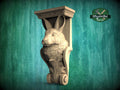 A carved wooden sculpture of a rabbit or hare head mounted on a wooden bracket against a green background.