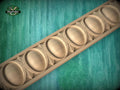 A wooden decorative border with a repeating pattern of oval shapes is displayed against a green background.