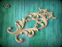 Load image into Gallery viewer, a decorative wooden carving with intricate scrollwork and floral elements, set against a green wooden background.
