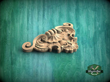Load image into Gallery viewer, A decorative wooden carving with intricate swirls and curves is displayed against a green background.
