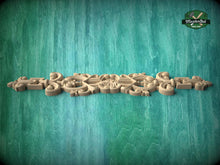 Load image into Gallery viewer, A decorative wooden carving or panel with intricate floral and scroll designs is displayed against a green textured background.
