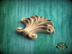 A wooden carving of a stylized flower or shell-like shape is displayed against a green background.