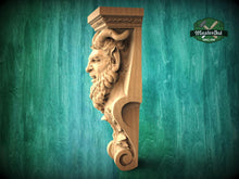 Load image into Gallery viewer, A carved wooden sculpture of a face with horns, set against a green background.
