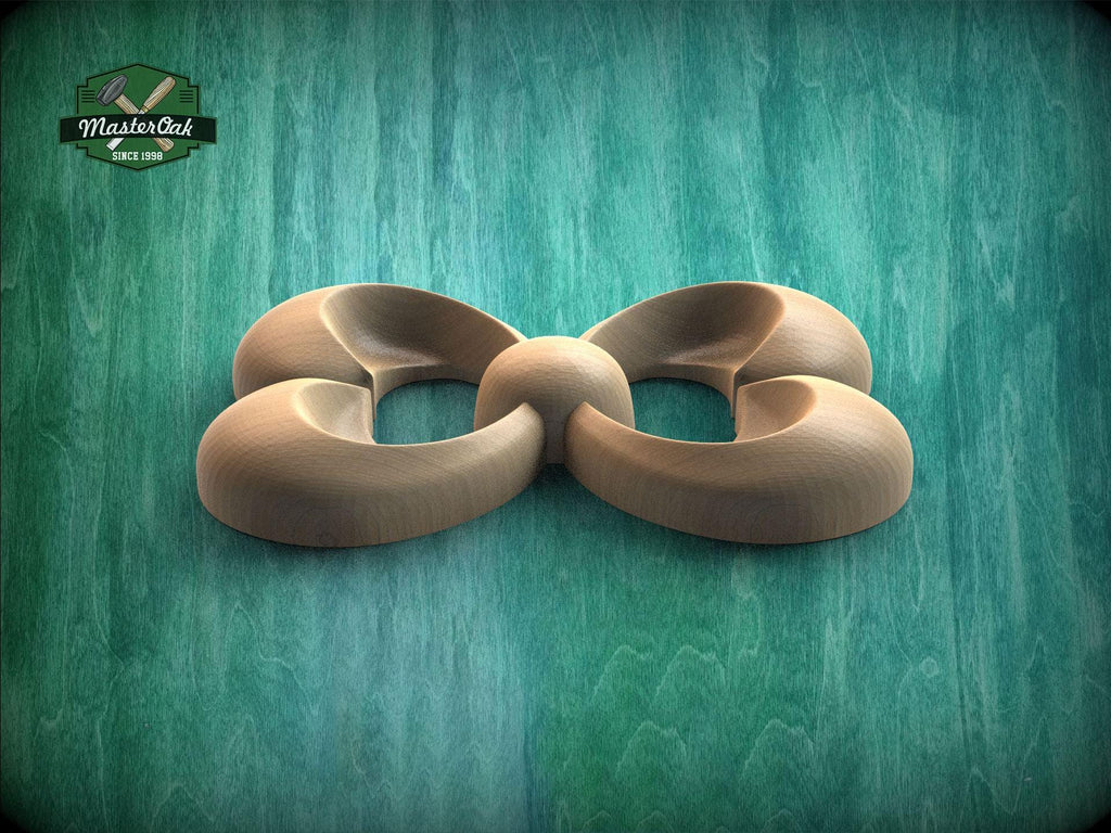 A wooden sculpture in the shape of a flower or bow, with curved petals and a round center, is displayed against a green background.