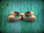 A wooden sculpture in the shape of a flower or bow, with curved petals and a round center, is displayed against a green background.