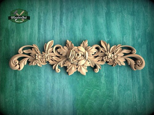 a decorative wooden carving of a rose and leaves on a green background.