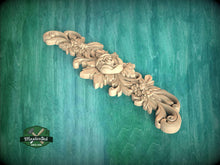 Load image into Gallery viewer, A decorative wooden carving with floral and leaf-like elements is displayed against a green background.

