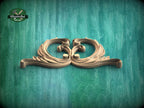 A decorative wooden ornament with an intricate, swirling design is displayed against a textured green background.