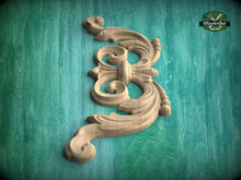Load image into Gallery viewer, A carved wooden ornament with an intricate, swirling design is displayed against a green background.
