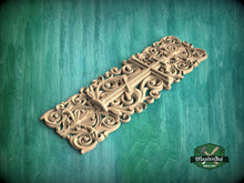 Load image into Gallery viewer, A decorative wooden carving with intricate scrollwork and floral patterns is displayed against a green background.
