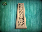 a decorative wooden panel with a carved design on a green background.