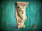 A carved stone sculpture of a fierce-looking face with horns, displayed against a green background.