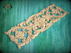 an ornate, carved wooden panel with intricate floral and scroll designs, set against a green background.