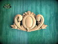 A wooden carving of an ornate, decorative piece is displayed against a green background.