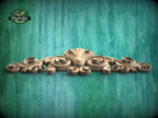 A decorative wooden carving with intricate scrollwork is displayed against a textured green background.