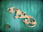 A decorative wooden carving with intricate floral and scroll designs is displayed against a green textured background.