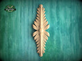 A decorative wooden leaf-like object is displayed against a green textured background.