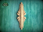 A decorative wooden leaf-like object is displayed against a green textured background.