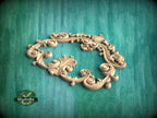 A decorative wooden frame with intricate scrollwork and floral patterns is displayed against a teal background.