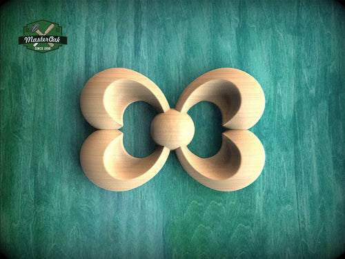 A wooden carving of a stylized flower or butterfly shape is displayed against a green background.