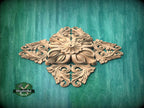 a decorative wooden piece with intricate carvings, displayed against a green wooden background.