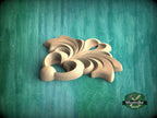 A wooden carving of a stylized flower or leaf design is displayed against a green background.