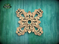 a decorative wooden piece with an intricate, symmetrical design on a green background.