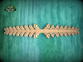 A decorative wooden leaf-like design is displayed on a green textured background.