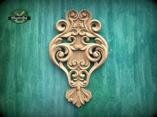 Load image into Gallery viewer, an ornate, carved wooden piece with intricate scrollwork and floral designs, mounted on a green wooden surface.
