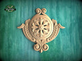 a beautifully carved wooden piece with a floral design, set against a green background.