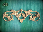 a decorative wooden carving with intricate floral and scroll designs, set against a green background.