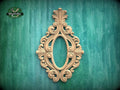 an ornate, carved wooden frame with an intricate, decorative design on a green background.