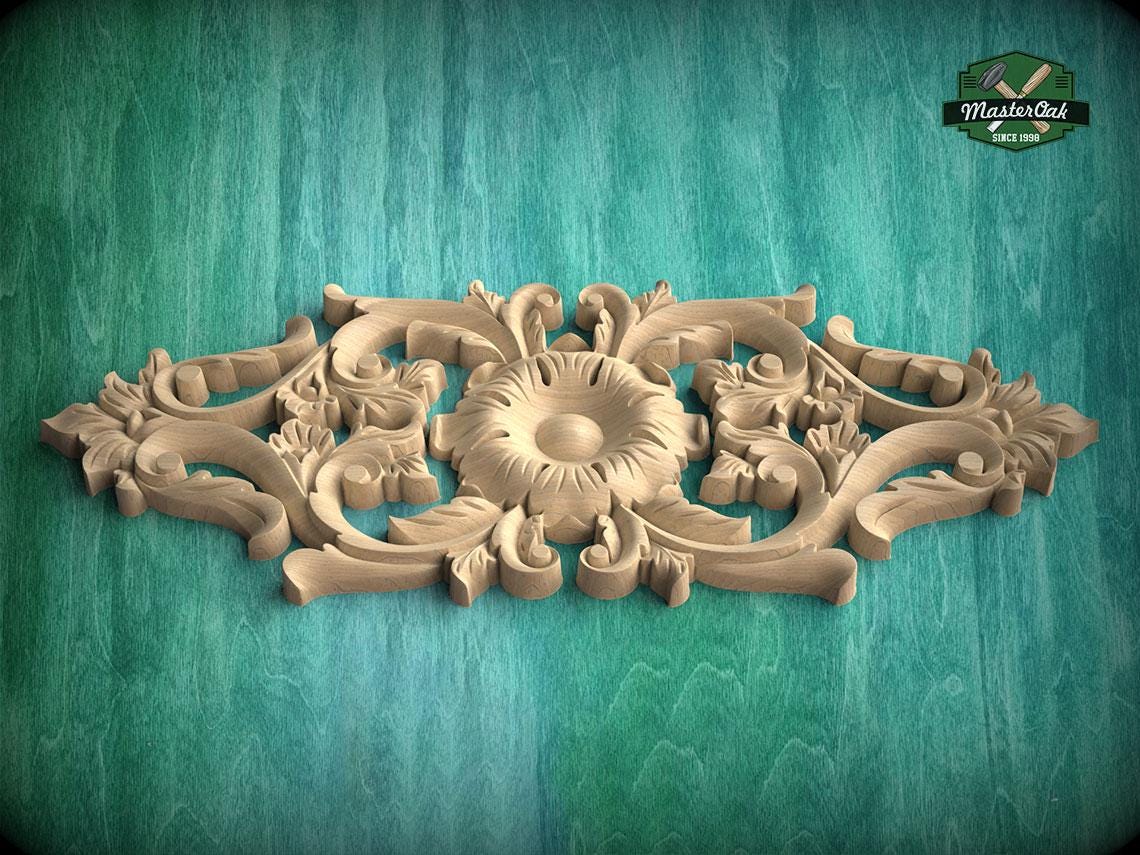 A carved wooden design with intricate floral and scrollwork patterns is displayed against a green textured background.