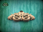 A decorative wooden carving with intricate scrollwork is displayed against a green textured background.