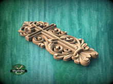 Load image into Gallery viewer, A decorative wooden carving with intricate floral and scrollwork designs is displayed against a green background.
