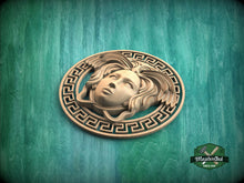 Load image into Gallery viewer, A wooden carving of a female head with flowing hair and a serene expression, encircled by a Greek key pattern, is displayed against a green background.
