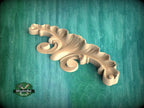 A wooden carving of a leaf-like design is displayed against a teal background.
