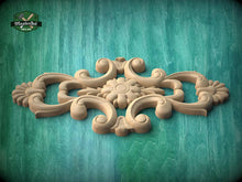 Load image into Gallery viewer, A decorative wooden carving with intricate floral and scrollwork designs is displayed against a green wooden background.
