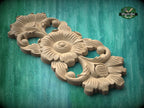 A wooden carving of a flower with intricate details, displayed on a green wooden surface.