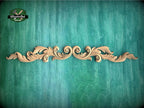 A decorative wooden carving with intricate scrollwork is displayed against a textured green background.