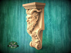 A carved wooden sculpture of a face with horns and a beard, mounted on a green wooden surface.