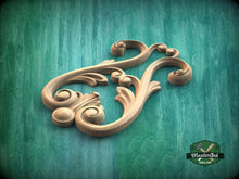 Load image into Gallery viewer, A decorative wooden carving with intricate scrollwork and floral elements is displayed against a green background.
