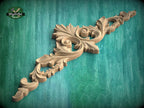 a beautifully carved wooden piece with intricate floral designs, displayed against a green background.