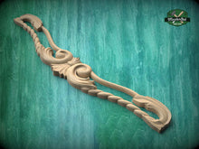 Load image into Gallery viewer, A wooden carving with intricate scrollwork is displayed against a green textured background.
