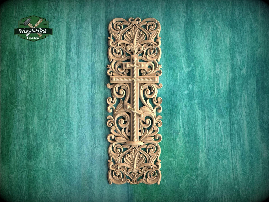 a decorative wooden cross with intricate floral and scrollwork designs, mounted on a green wooden surface.