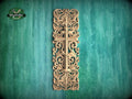 a decorative wooden cross with intricate floral and scrollwork designs, mounted on a green wooden surface.