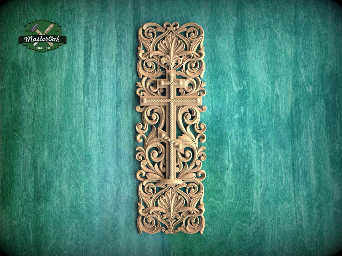 a decorative wooden cross with intricate floral and scrollwork designs, mounted on a green wooden surface.